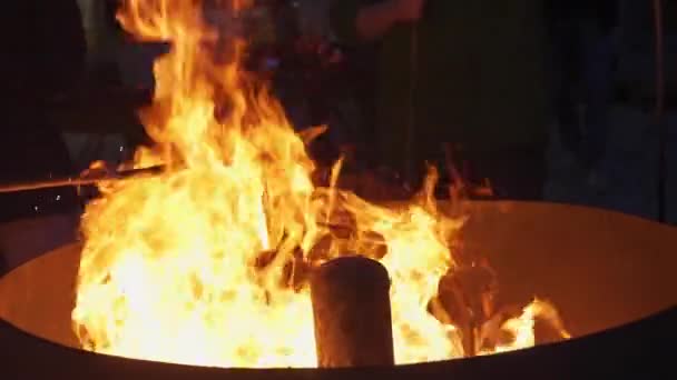 人々は夜のパーティーを楽しむためにたき火の上にソーセージを焼く — ストック動画