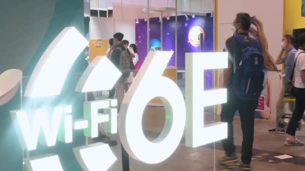 中国からの観光客は 香港で開催された香港コンピュータ通信フェスティバルで6E Wifi高速インターネットロゴを展示するブースを通り過ぎます — ストック動画