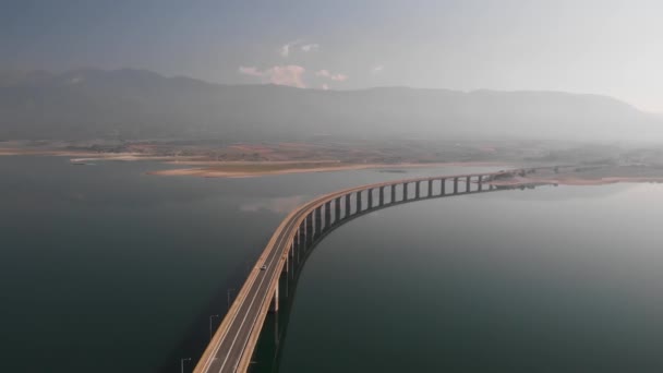 Letecký Panning Shot Long Lake Bridge Hory Automobilovou Dopravou Mlhavé — Stock video