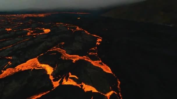 Fpv无人驾驶飞机在炽热的熔岩地面和火山上空低空飞行 在黑暗的一天点燃了岩石 — 图库视频影像