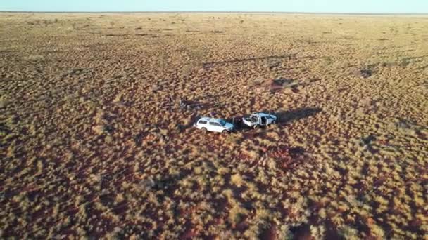 オーストラリア ノーザンテリトリーのタナミ砂漠で2台の車と人々の空中映像を反転させ 上昇させます 2022年8月 — ストック動画