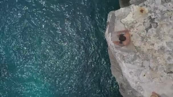 Rising Overhead Slo Aerial Man Cliff Jumps Twist Sea — Stock Video