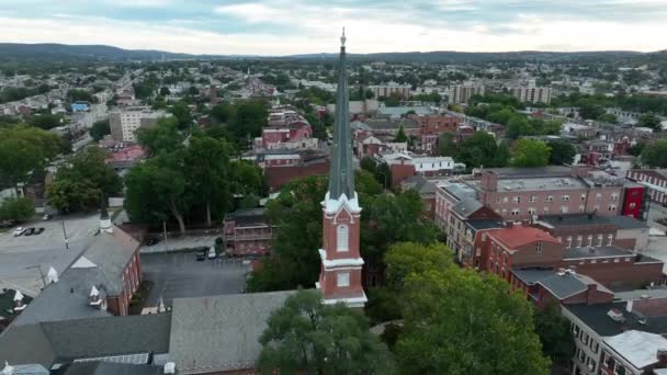 アメリカの教会の尖塔の空中軌道 夏の夕方の曇りの空の間のアメリカの都市 — ストック動画