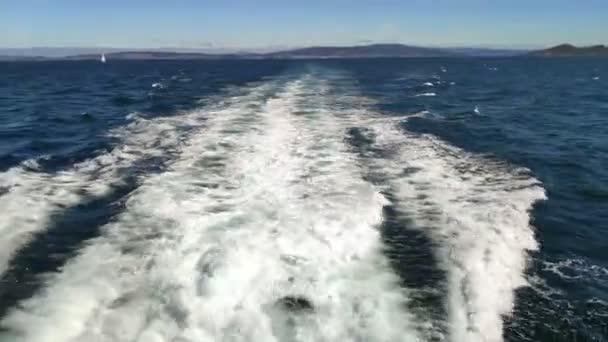 在白沙角晴朗的蓝天里 船尾的尾迹与陆地和一艘帆船在背风中航行 在西班牙加利西亚Pontevedra被截住了 — 图库视频影像