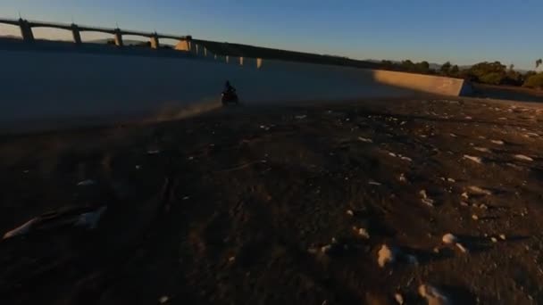Fpv无人驾驶飞机跟踪着骑在Sepulveda大坝顶上的自行车人影 穿过洛杉矶落日的阳光 — 图库视频影像