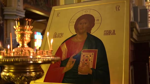 カザフスタンのゼンコフ大聖堂内の正教会のアイコンの横に燃えるキャンドル — ストック動画