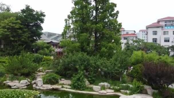 从威海市一个美丽的中国花园池塘看黄居区城市景观的空中快速上升 — 图库视频影像