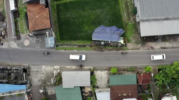 一辆卡车侧卧着 在印度尼西亚的一条住宅公路旁翻倒了 汽车和摩托车驶过 自上而下的无人驾驶飞机射击 — 图库视频影像
