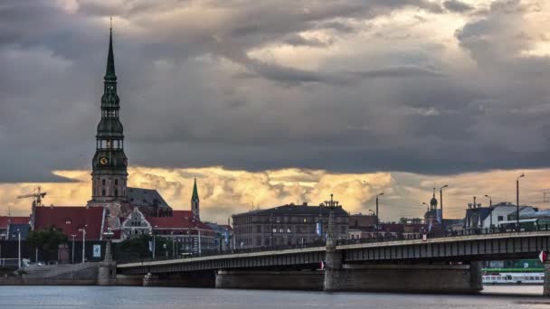 ラトビアのリガにあるドーヴァ川を渡る聖ピーターズ教会と石の橋の鐘楼の上を移動する雲 経過時間 — ストック動画