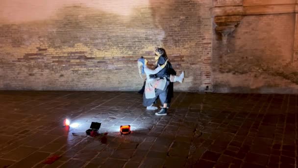 2体の人形の中に隠されたストリートアーティストのコミックショーは 街の通りで夜に情熱的なダンスを一緒に演奏 — ストック動画