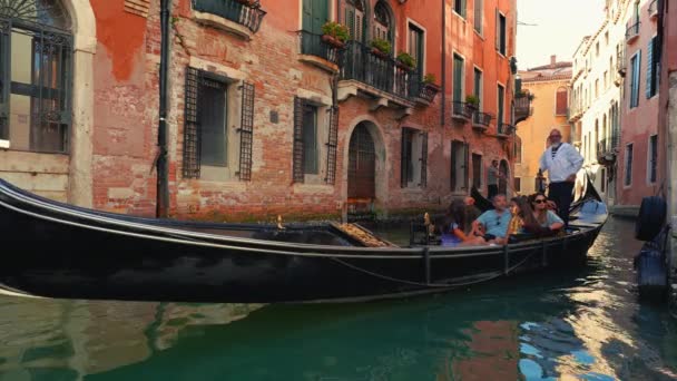 ゴンドラボート ゴンドラ ヴェネツィアの運河の観光客 古い家とサンマルコ大聖堂教会とリアルト橋に近いイタリア 象徴的なヴェネツィアの夏のカーニバル旅行の場所 — ストック動画