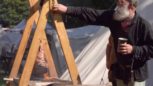Medieval Reenactment Men Cooking Hanging Lamb Leg Being Roasted Open — Stock Video