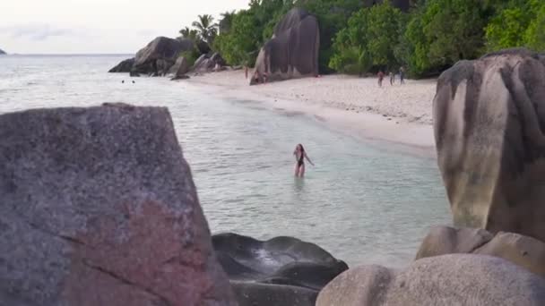Жінка Чорному Купальнику Стоїть Воді Пляжі Сейшельські Острови Валунами Заході — стокове відео