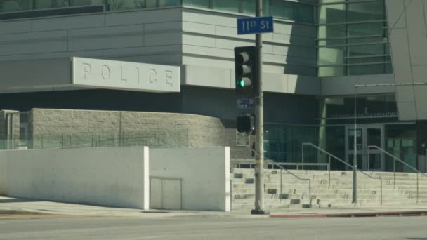 交通信号と左側の警察看板を示す 都市の11番街の警察本部前を通過する車を示す距離から撮影されたパースペクティブ — ストック動画