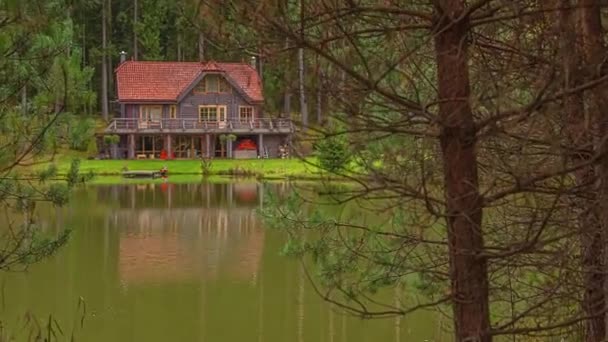 湖のほとりの春の風景に沿って美しい湖畔のロッジのダウンショットを傾けタイムラプス — ストック動画