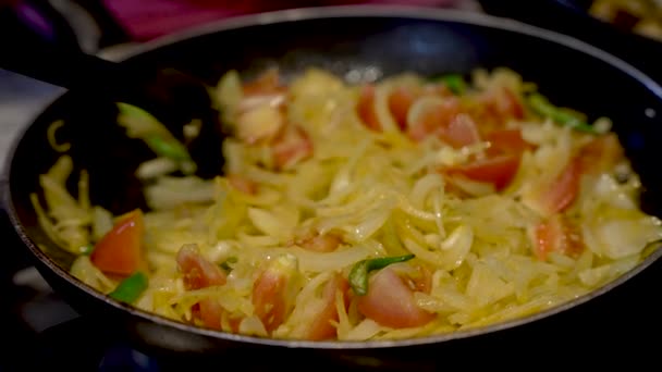 在厨师搅拌洋葱 切碎的西红柿和辣椒时 在热腾腾的平底锅周围用慢镜头拍摄的油锅镜头 以确保蔬菜的烹调均匀 — 图库视频影像