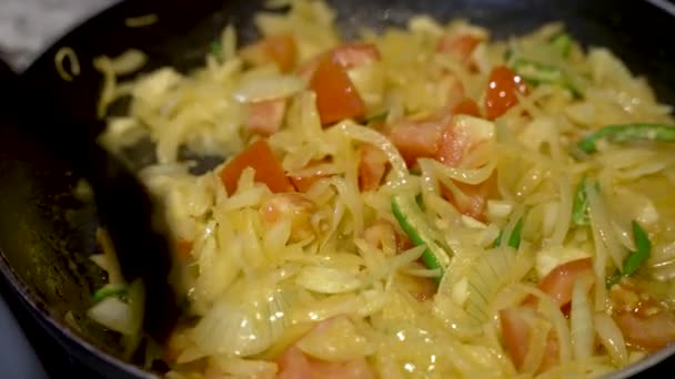 在厨师搅拌洋葱 切碎的西红柿和辣椒的过程中 在热腾腾的平底锅周围放上一道低角度的油锅镜头 以确保蔬菜的烹调均匀 — 图库视频影像