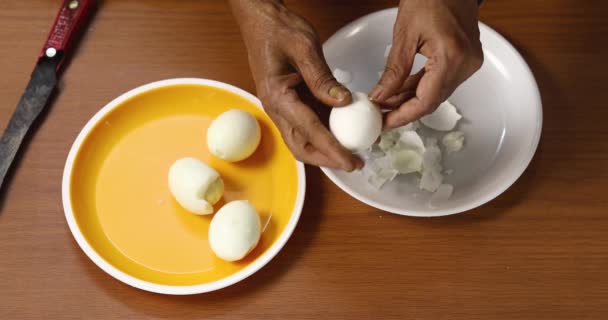 一个女人用锋利的小刀敲敲煮熟的鸡蛋 把剥皮的鸡蛋和剥皮的蛋壳分开 顶部视图 — 图库视频影像