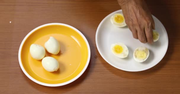 一个女人从一个黄色的盘子里取出煮熟的鸡蛋 装饰一个白色的盘子 在盘子里手工装饰煮熟的鸡蛋 特写镜头 顶视图 — 图库视频影像