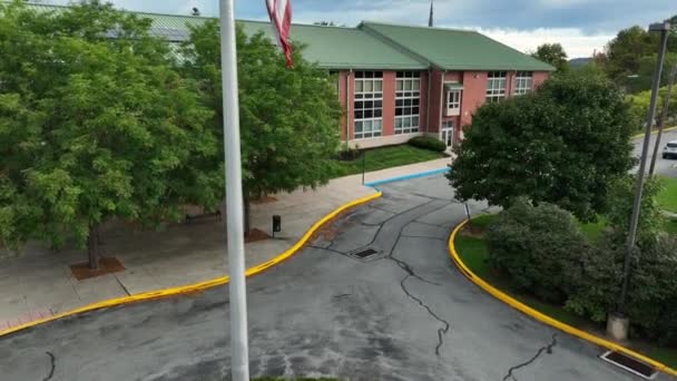 アメリカの近代公立学校でアメリカ国旗 小さな町アメリカの教育テーマ 空中暴露 — ストック動画