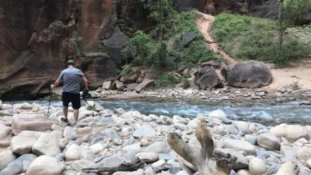 ナローズのシオン国立公園でカメラを手に石の上を歩く男 — ストック動画