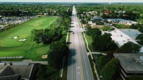 在一个阳光明媚的日子里 一架无人驾驶飞机在美国伊利诺伊州北部的高尔夫俱乐部旁边的一条长长的公路上盘旋而过 — 图库视频影像
