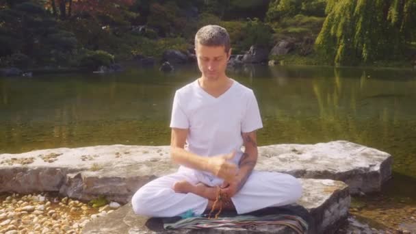 Білий Білий Чоловік Практикує Медитацію Сидячи Скелі Біля Ставка Пишному — стокове відео