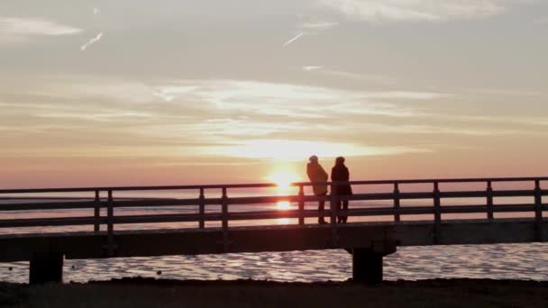 二人の女性は 干潮の間 北海の高架橋で日没を待ちます — ストック動画