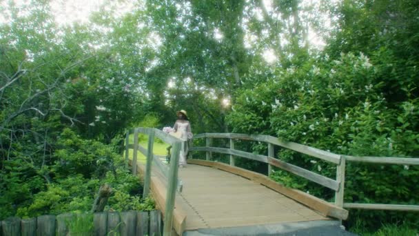 Black Woman Picnic Basket Walking Bridge Smelling Flowers Lilacs Wide — Vídeo de stock