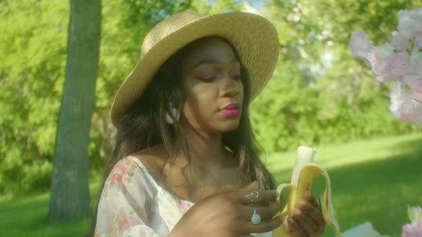 Μαύρη Γυναίκα Τρώει Μια Μπανάνα Στο Πάρκο Και Κάνει Κύκλους — Αρχείο Βίντεο