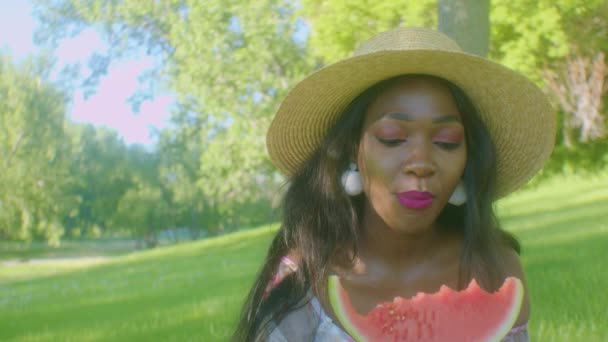 Черная Женщина Кусает Арбуз Наслаждаясь Пикнике Парке Солнечный День — стоковое видео