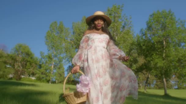 Black Woman Wearing Summer Dress Sun Hat Stroll Park Basket — Vídeos de Stock