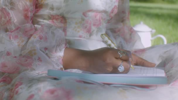 Black Woman White Floral Dress Park Writes Her Diary Close — Stock Video
