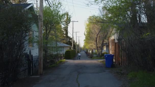 Wide Establishing Shot Suburb Alley Road Kids Distance Riding Bicycles — Vídeos de Stock