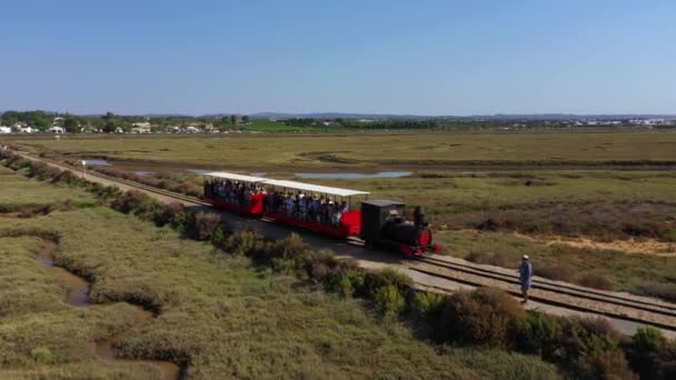 ポルトガルのタビラへのトラック上の人々でいっぱいのバリービーチ列車を追跡する空中ビュー — ストック動画