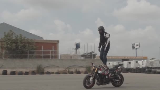 摩托车特技骑手站在自行车顶上 身穿黑色衣服 头戴安全帽 动作缓慢 时速120英尺 — 图库视频影像