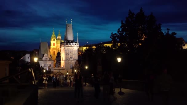観光客とプラハのカレル橋の夕景 ストラナ橋の塔を見て — ストック動画