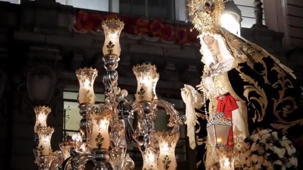 在西班牙马德里举行的圣周庆祝活动期间 圣母玛利亚乘坐马车的特写镜头飘扬在空中 游行正在摇曳着夜晚灯笼点亮的身影 建筑物后面有欧罗巴旗 — 图库视频影像