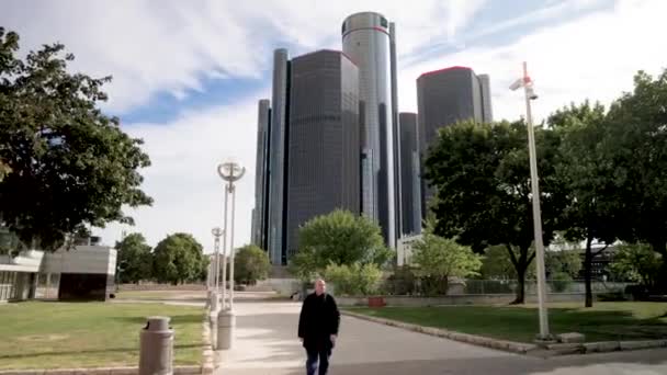 Pria Berjalan Menuju Kamera Dengan Renaissance Center Detroit Michigan Latar — Stok Video