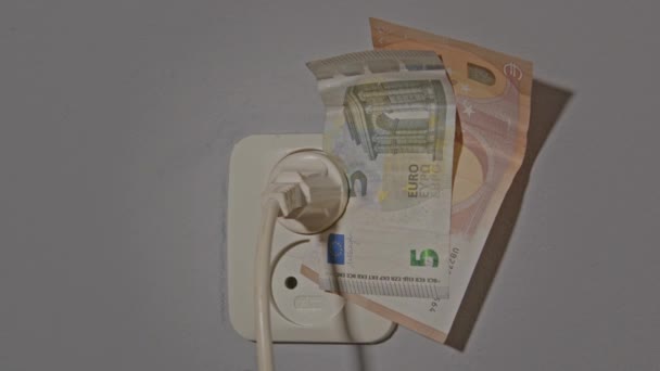 エネルギー危機の概念 電気コンセントへのプラグで保持されているユーロ紙幣のズームアウト — ストック動画