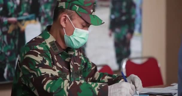 インドネシア国軍の男性医師は 病院の前の登録デスクで女性看護師によって支援され 患者を作成または登録しています — ストック動画