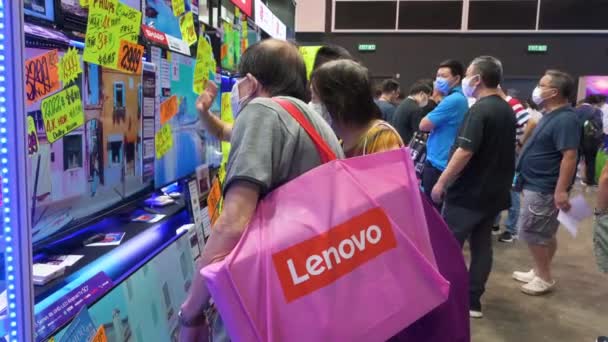 一名中国买家在购买打折电子产品时 拿着一个联想集团购物袋浏览在香港电脑及通讯节期间展出的电视机 — 图库视频影像