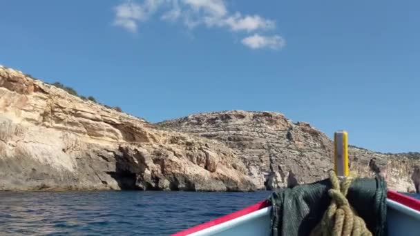 在阳光明媚的夏日 传统的卢祖渔船在马耳他蓝色石窟海岸附近的地中海海底海浪中摇曳 — 图库视频影像