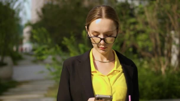 办公室工作人员女性成年人在夏日站在公园里看手机屏风 肖像前景 — 图库视频影像