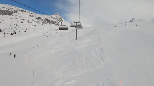 チェアリフト雪に覆われた山のリゾートでスキー場の上に移動します 斜面を滑り降りると — ストック動画