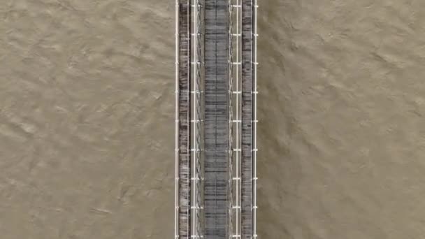 洪水泛滥泥石流之上的旧悬索桥自上而下的空中景观 — 图库视频影像