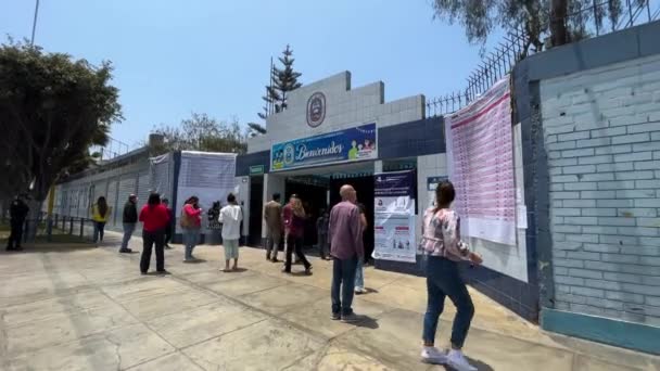 在秘鲁利马的La Molina 在平静晴朗的日子里 向平静地进入投票站的秘鲁选民开枪射击 男人看信息海报 — 图库视频影像