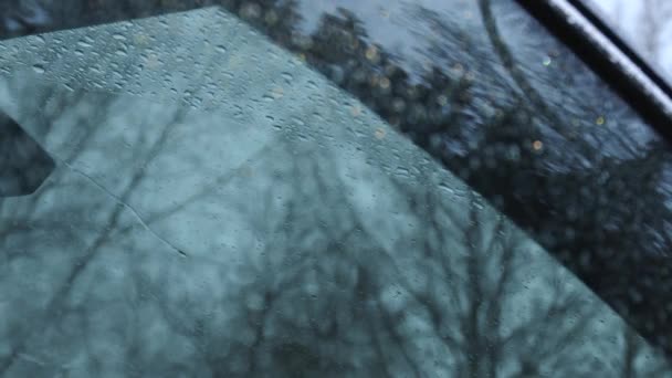 雨が冷たい雨の日に落ちるワイプながら 駐車車のフロントガラスに雨滴の静的なタイトなクローズアップ — ストック動画