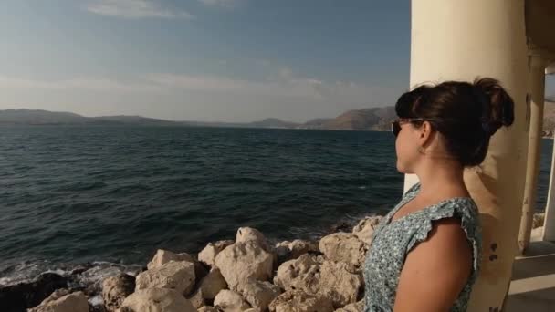 Жінка Коричневому Волоссі Зеленій Сукні Стоїть Колоні Маяка Насолоджується Видом — стокове відео