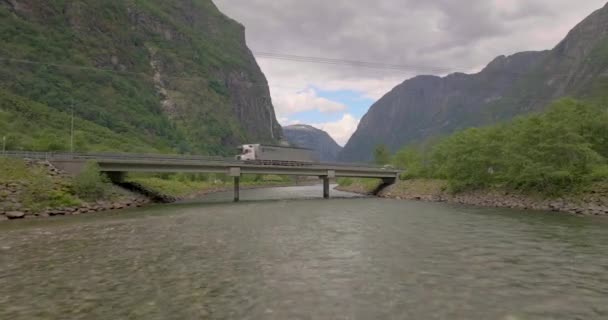 ノルウェーの背景にある渓谷と道路橋Gudvangen川に向かって飛んでいます 空中ドローンショット — ストック動画